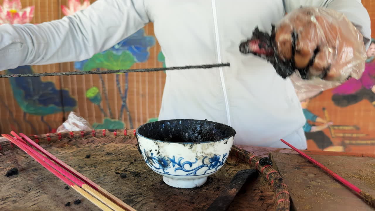 A person rolling incense sticks at the Hà Nội Quảng Phú Cầu Incense Village, surrounded by incense powder and materials