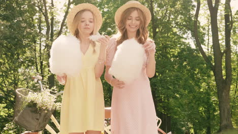 two friends enjoying cotton candy in the park