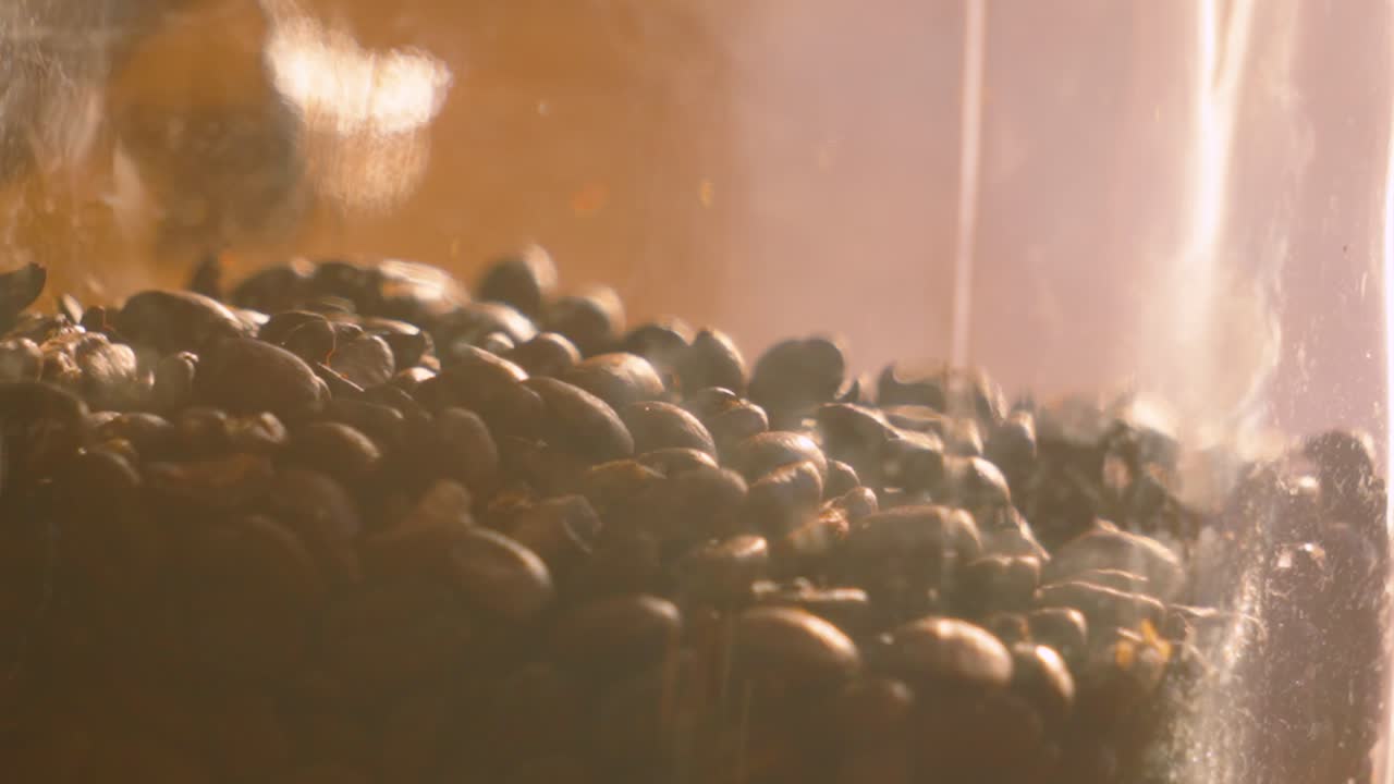 Sunlit Whole Brown Roasted Coffee Beans in Glass Jar Falling in Slow Motion Background. Close Up Fresh Hot Drink Natural Ingredients Ready to Blend and Enjoy.