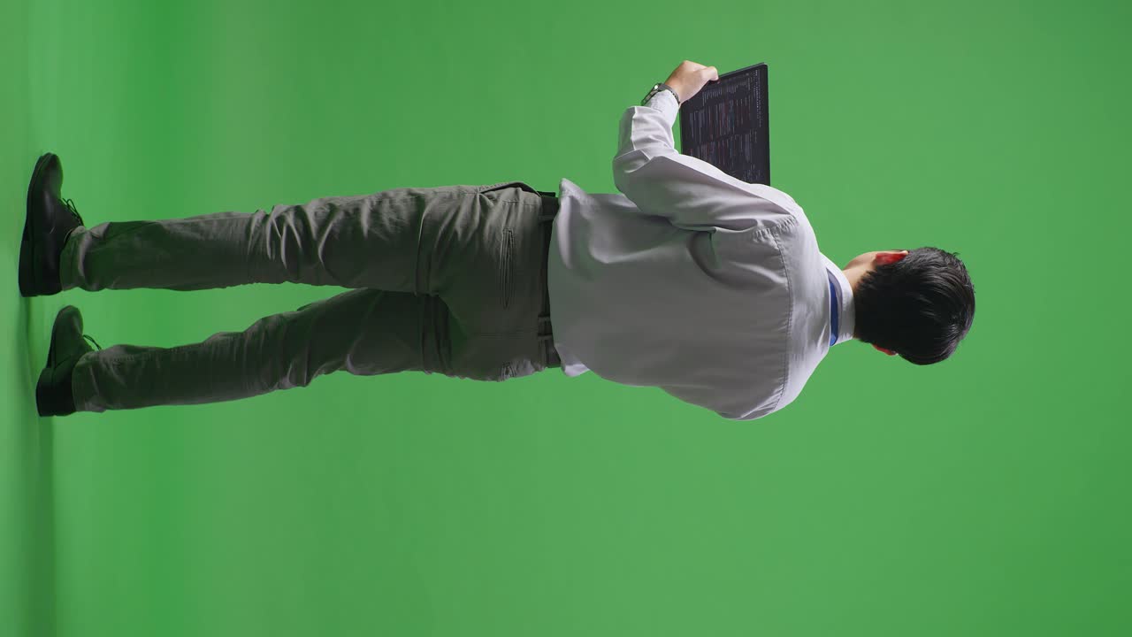 비즈니스맨이 녹색 화면에서 태블릿을 읽고 있습니다.