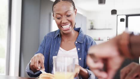 happy african american couple having breakfast and talking at table in kitchen, slow motion