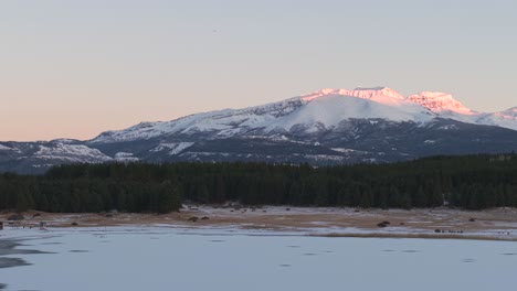 smooth panoramic movement at laguna la zeta on frozen lake and forest side with distant glowing mountain peaks, esquel, province of chubut, argentina