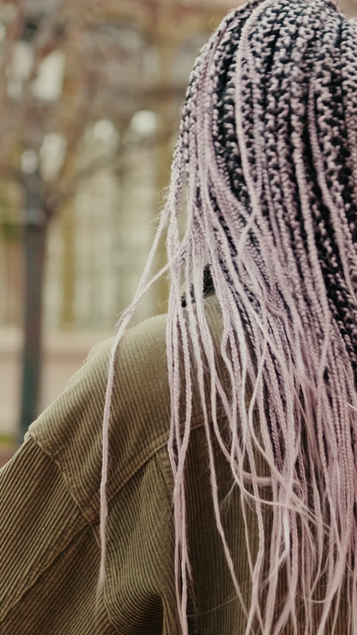 Giovane donna con lunghi capelli intrecciati che si guarda intorno all'aperto