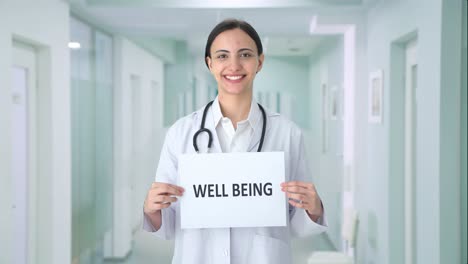 happy indian female doctor holding well being banner