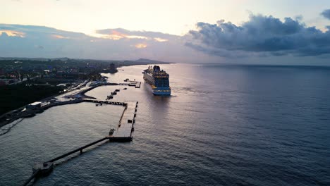 Wide-angle-rear-view-trucking-pan-across-cruise-shop-docked-at-Caribbean-port-at-dusk