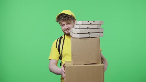 retrato de hombres jóvenes sosteniendo paquetes y cajas de pizza. hombre pelirrojo en uniforme de mensajero de entrega amarillo con bolsa térmica posando en pantalla verde en el estudio. primer plano. cámara lenta lista 59,97 fps