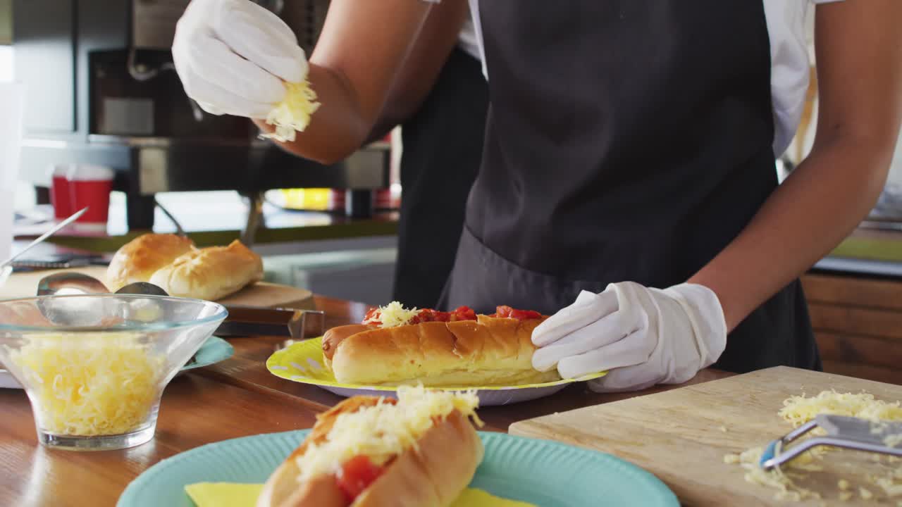 식품 트럭에서 핫도그 위에  ⁇ 은 치즈를 넣는 아프리칸 아메리칸 여성의 중간 섹션