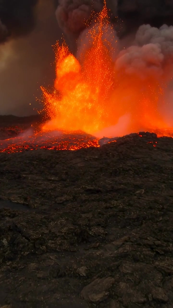 Video verticale: Eruzione dopo l'aumento di pressione, fontana di lava che spara schizzi incandescenti dalla bocca del vulcano, pennacchio di cenere.