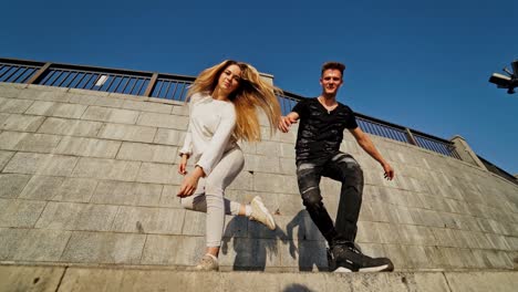 happy teens near the wall. young man in black and woman in white outdoors. slow motion. view from below.
