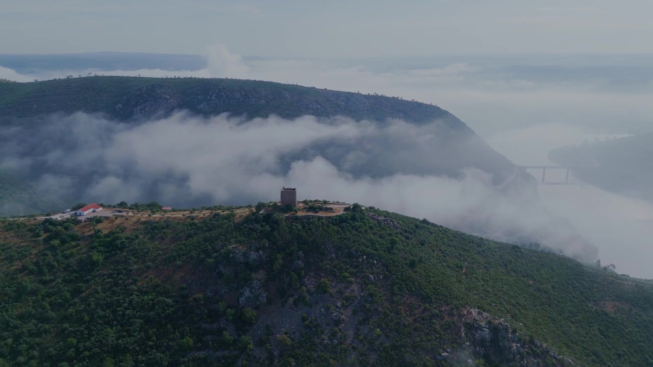 Horisontell drönarorbit runt Castelo de Rodao nära Portas do Rodao, Portugal, som avslöjar landskapet, bron över floden Tejo och morgondimman som omger slottet