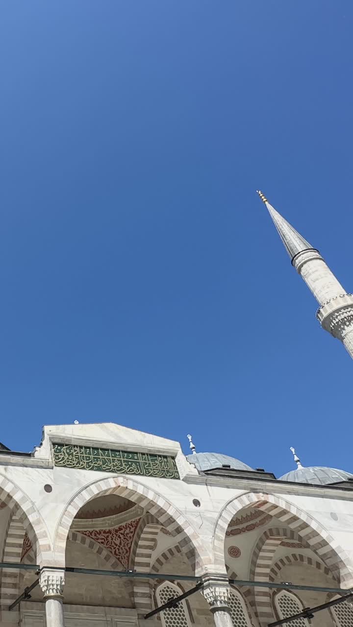 Push along entrance to Suleymaniye Mosque, tall towers in background at midday