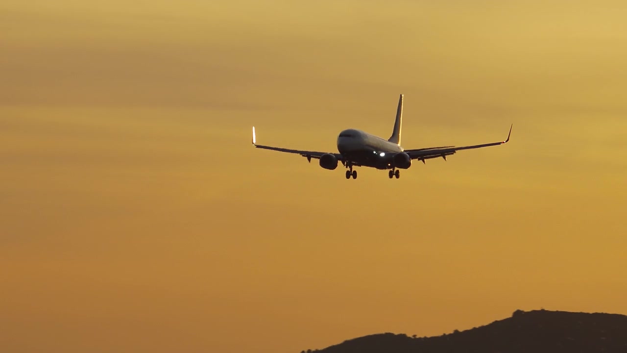 Silhouette di un aereo passeggeri in avvicinamento per l'atterraggio al tramonto