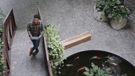 High-angle-view-of-african-american-male-designer-using-tablet-in-casual-office,-slow-motion