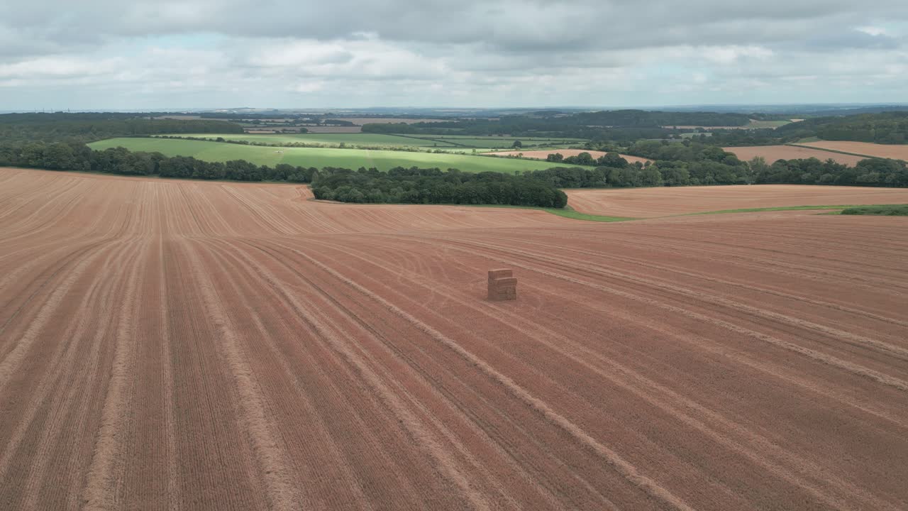 Panoramische Luftaufnahme von Feldlinien unterhalb des Farley Mount Monuments, Winchester, Großbritannien, umgeben von abgeernteten Feldern und natürlichem Grün