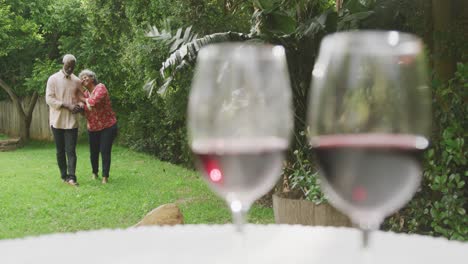 a senior african american couple enjoying a glass of wine in social distancing