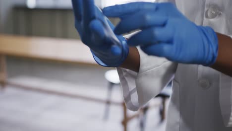 médico de raza mixta poniendo sus guantes de protección