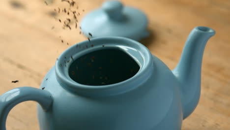 loose tea pouring into blue teapot