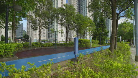 Slow-motion---Blue-cycle-path-near-garden-of-residential-apartment-towers