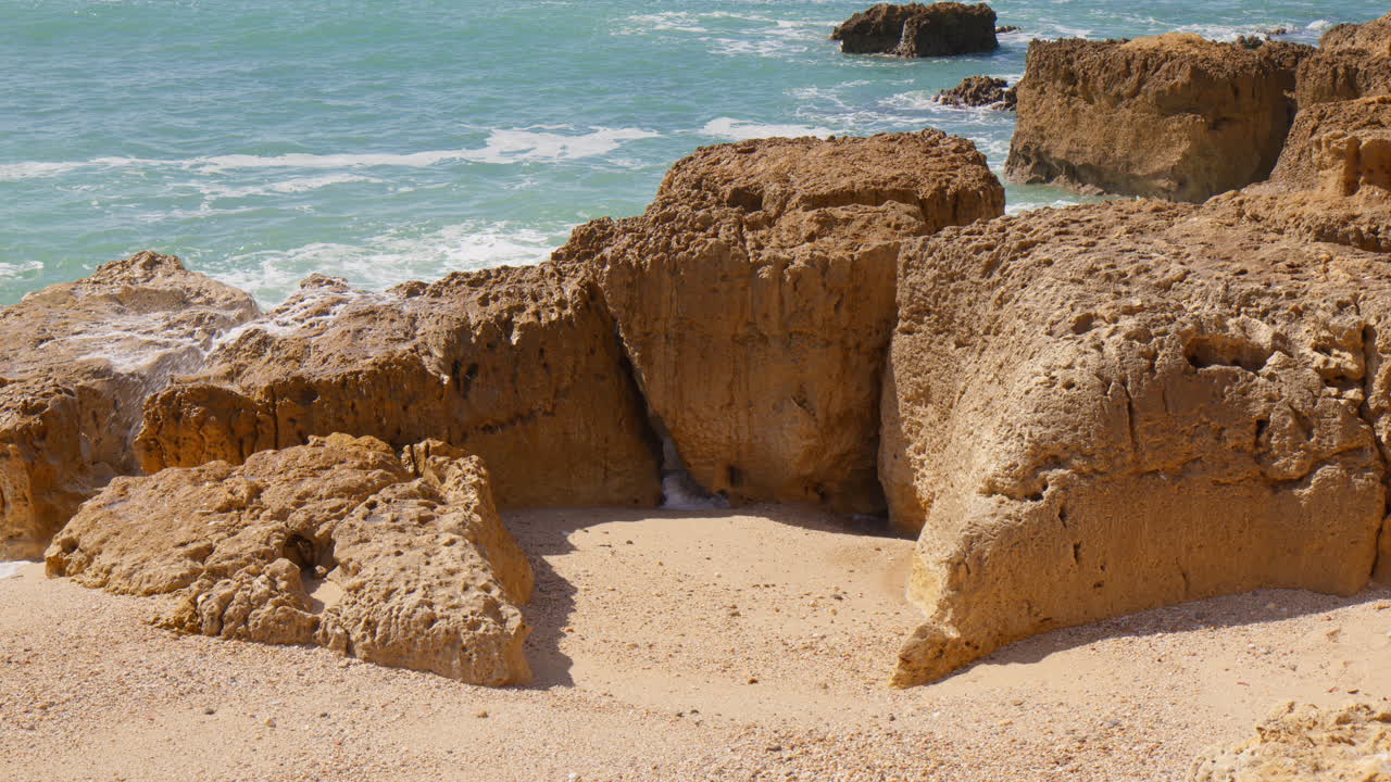Onde si infrangono sulle scogliere di arenaria della spiaggia di Praia do Evaristo ad Albufeira, Algarve, Portogallo.