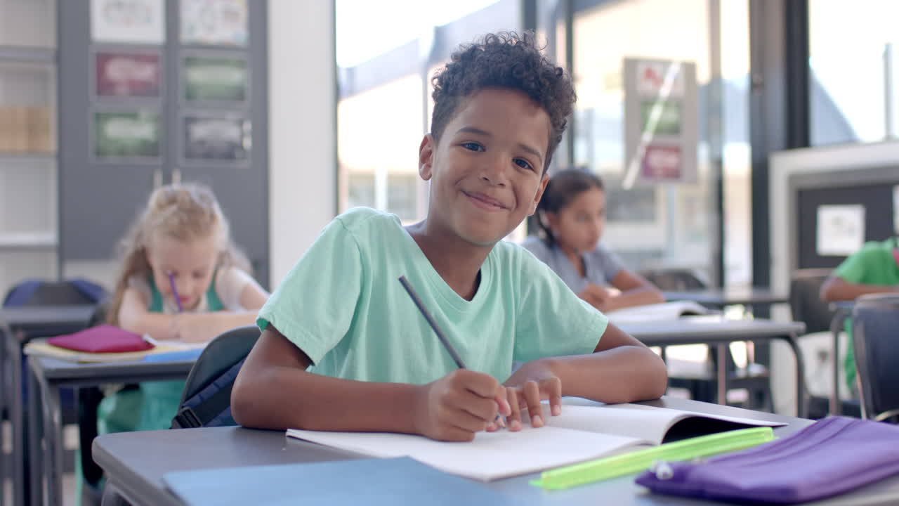 Biracial boy smiles while studying in school in the classroom