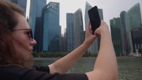 mujer tomando una foto de rascacielos en la ciudad