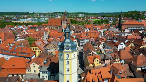 4k aerial drone video of the historic herrieder clock tower and the st. johannis church in the old town area of downtown ansbach, germany