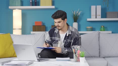trabajador de oficina en casa tomando notas mientras mira la computadora.