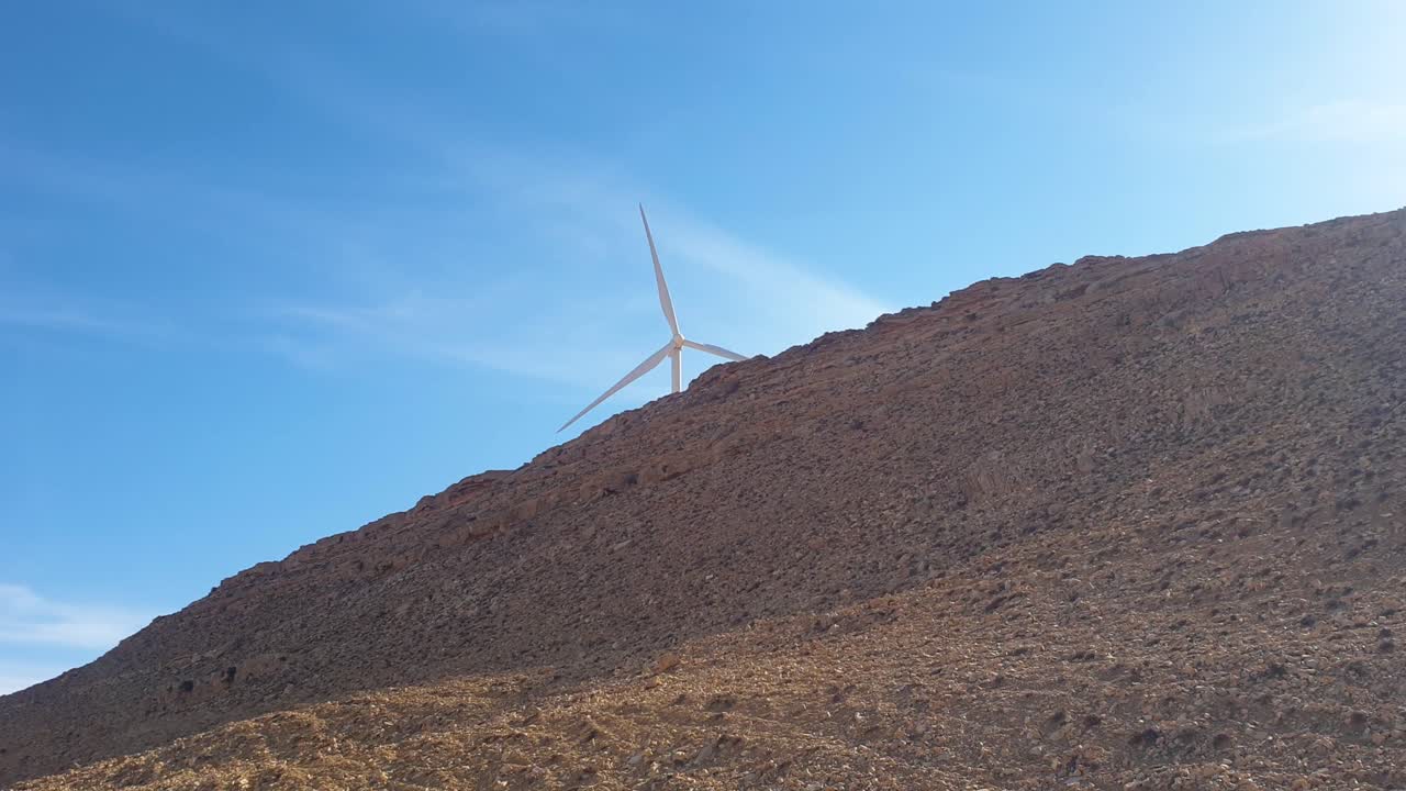 turbina eólica en solitario girando en el remoto desierto árabe y paisaje montañoso en jordania, oriente medio