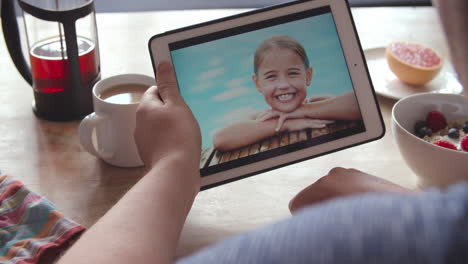 Person-At-Breakfast-Looking-At-Photos-On-Digital-Tablet