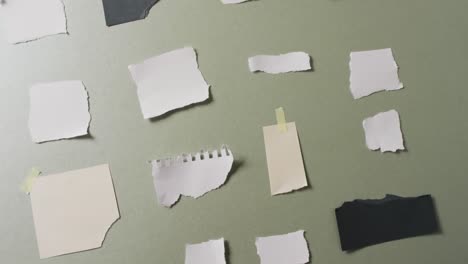 Video-of-close-up-of-multiple-torn-pieces-of-paper-on-green-background