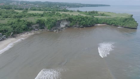 drone aéreo disparado sobre agua fangosa contaminada y basura flotante y escombros mezclándose con agua turquesa y costa tropical en bali indonesia