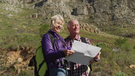 active senior couple looking map on mountains