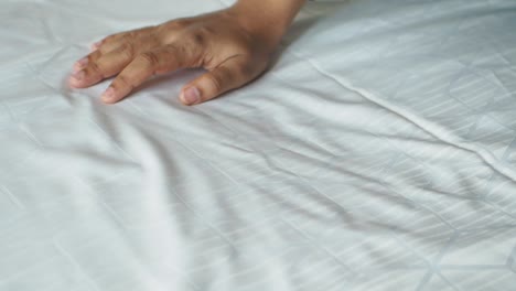 la mano tocando una sábana blanca