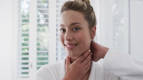 Happy-biracial-woman-touching-her-face-in-bathroom,-slow-motion