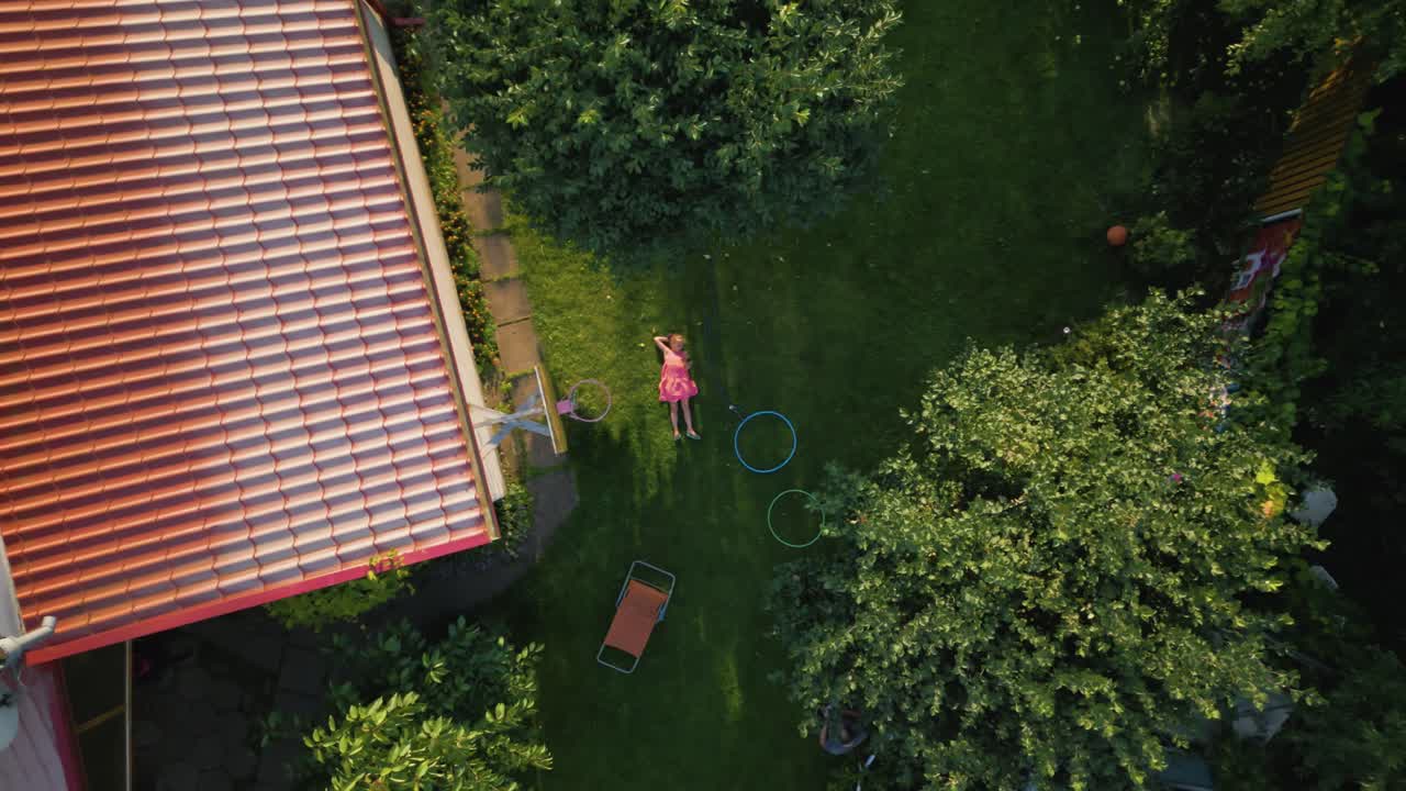Overhead shot of little girl relaxing in the backyard of her home