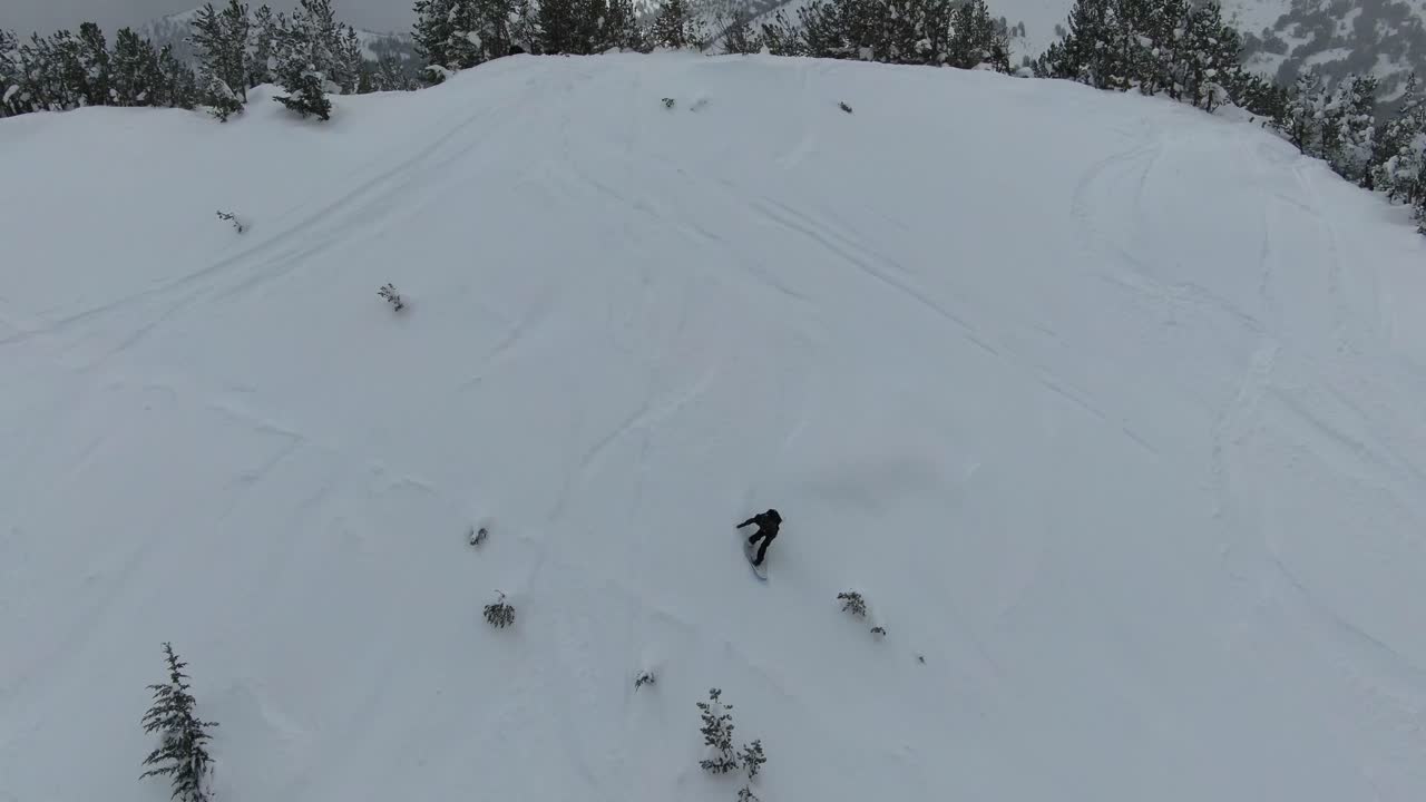 imágenes aéreas de 4k de un snowboarder bajando una colina empinada en el interior nevado de las montañas de la sierra nevada en el lago tahoe