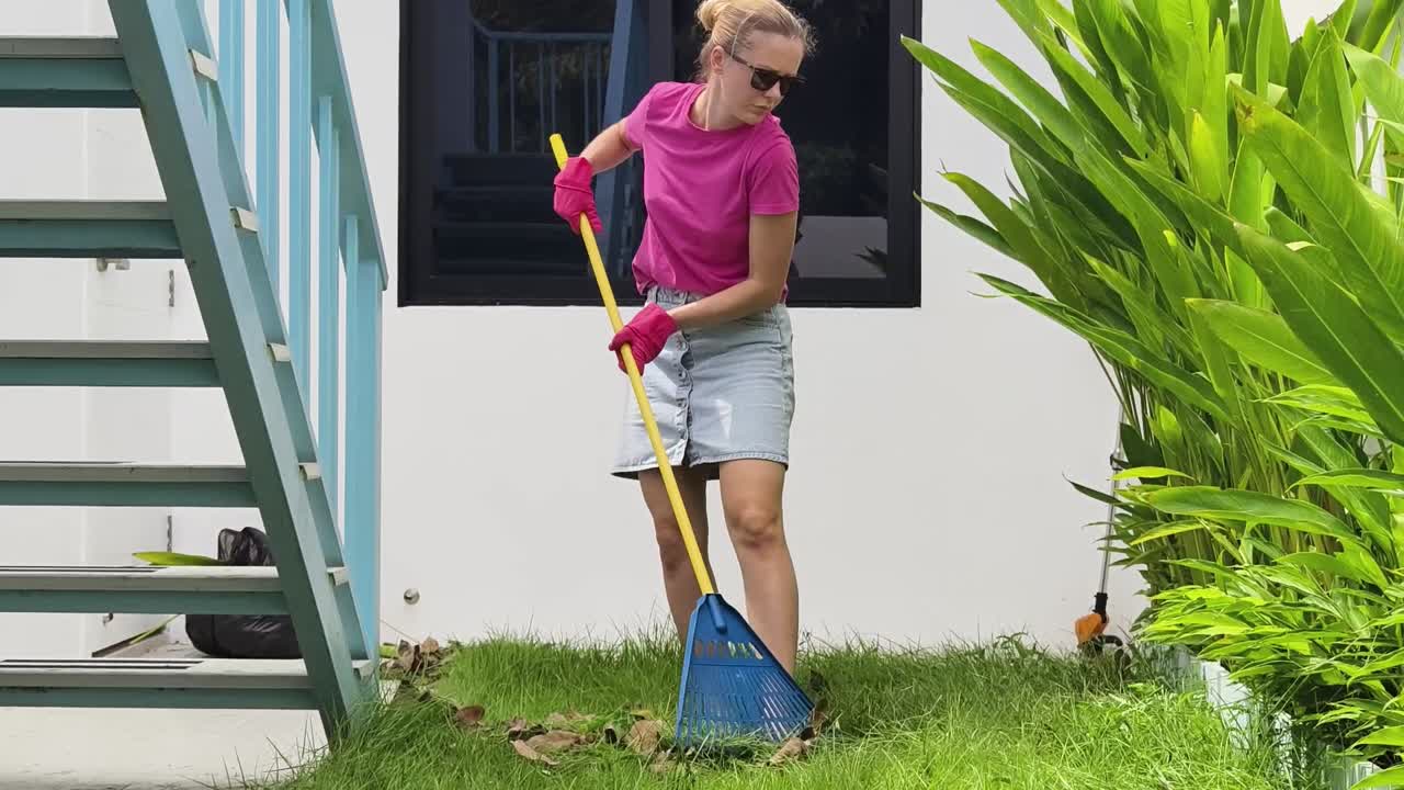 mujer rastrillando hojas en un jardín