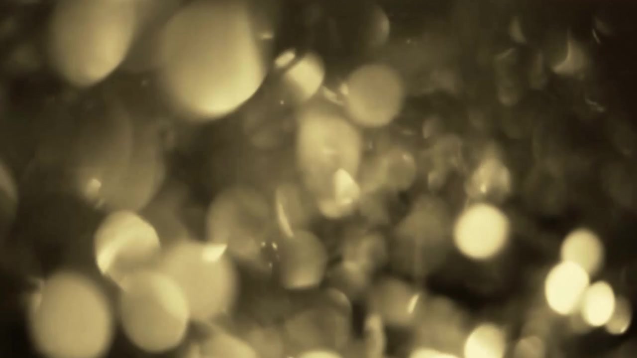 Abstract Golden Light Bokeh Particles Floating in Dark Background