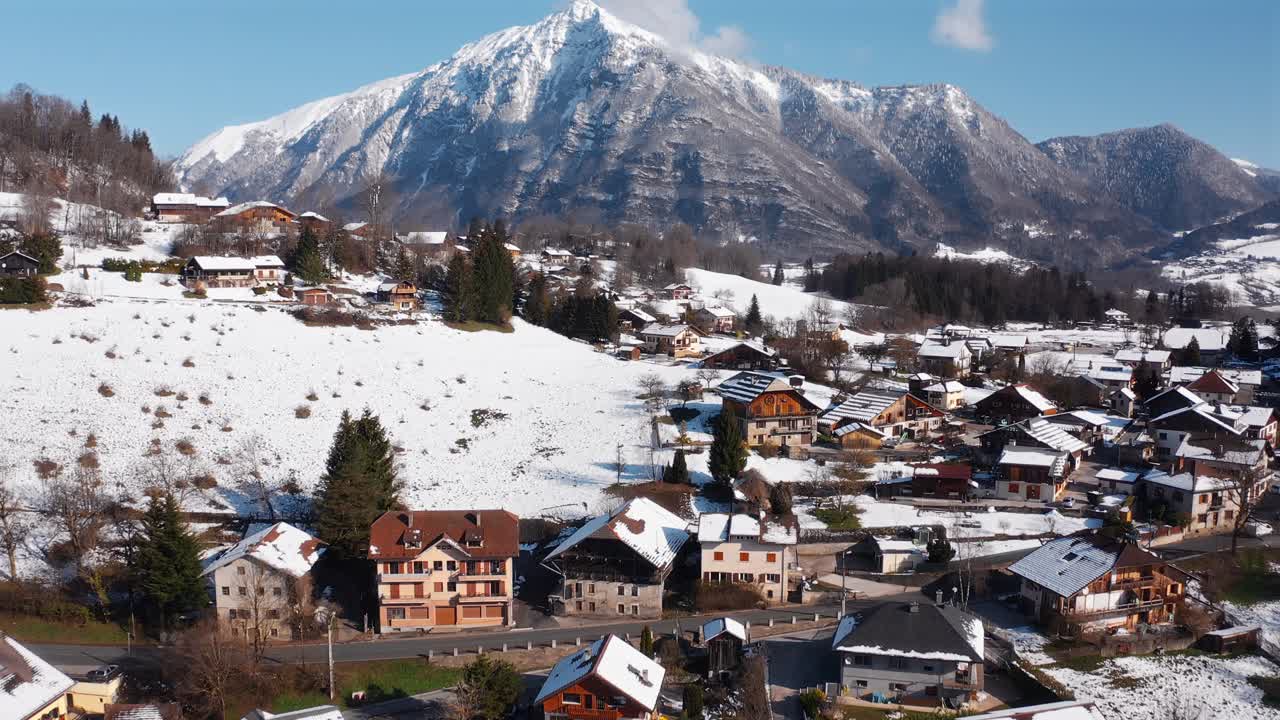 Push in, tilt up drone shot of the snow covered village of Châtillon sur Cluses towards the beautiful peak of Marcelly on a blue bird pow day in Haute-Savoie, France