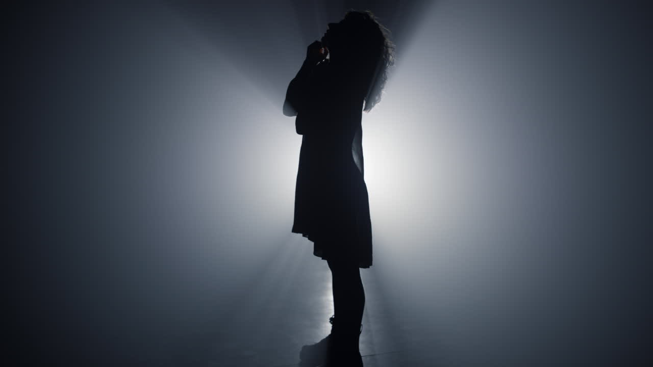 silhueta mujer delgada mirando hacia arriba en el interior. niña hermosa de pie en el espacio oscuro.