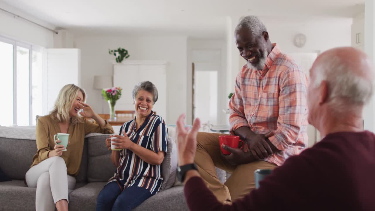 Two diverse senior couples sitting on a couch drinking tea together at home