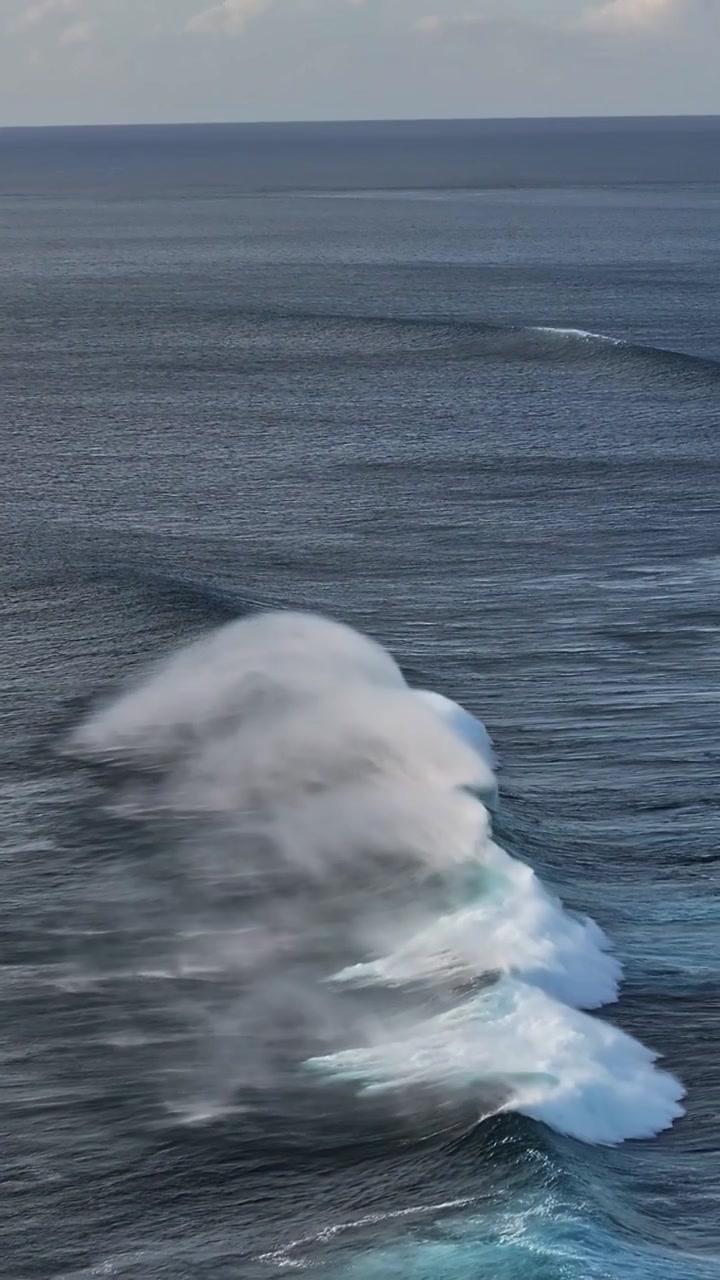 Onde con la cresta bianca si infrangono con forza nell'oceano aperto, creando uno spruzzo drammatico. Ideale per documentari naturalistici o studi oceanici