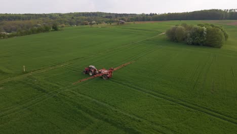 imágenes aéreas de drones circulares de un tractor rociando un enorme prado verde con agua o pesticida con su sistema de rociadores