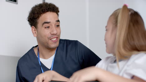 un joven enfermero biracial en trajes médicos interactúa con una chica caucásica.