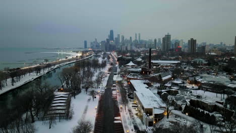 Aerial-view-rising-over-the-Cannon-Drive,-towards-the-skyline-of-Near-North-Side,-slushy,-winter-evening-in-Lincoln-park,-Chicago,-USA