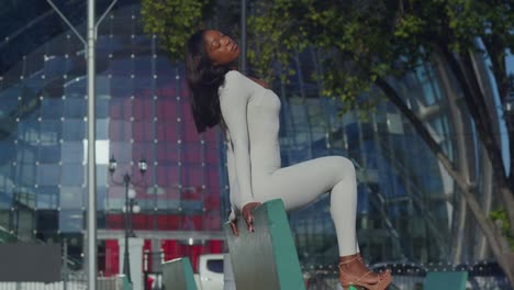 a young girl in a white bodysuit enjoys her city day with glass building in the background