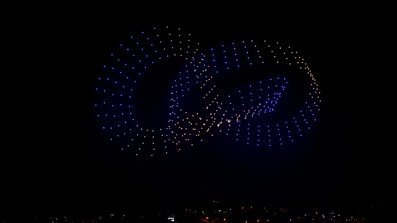 Flying drones creating 3d models moving on night sky over the city lights, exceptional show