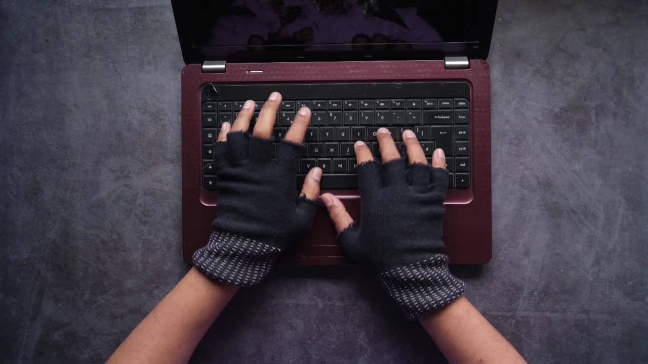 persona escribiendo en una computadora portátil con guantes
