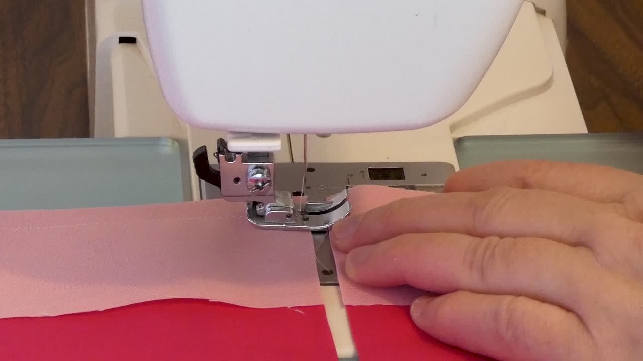 A woman chain-pieces seams on a sewing machine.