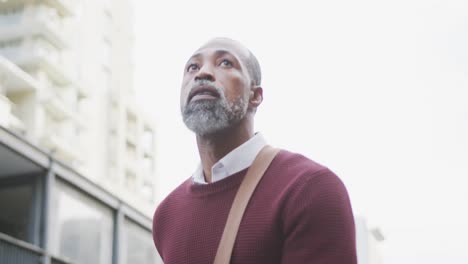 African-American-man-out-and-about-in-the-city-streets-during-the-day,-walking-in-the-street-and-whe